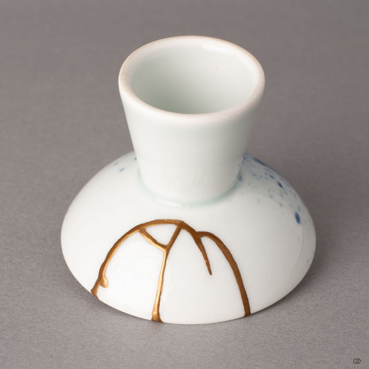 Close-up of a gold kintsugi line along the exterior of an Arita sake cup, where urushi lacquer meets sometsuke blue, crafted resilience made visible.