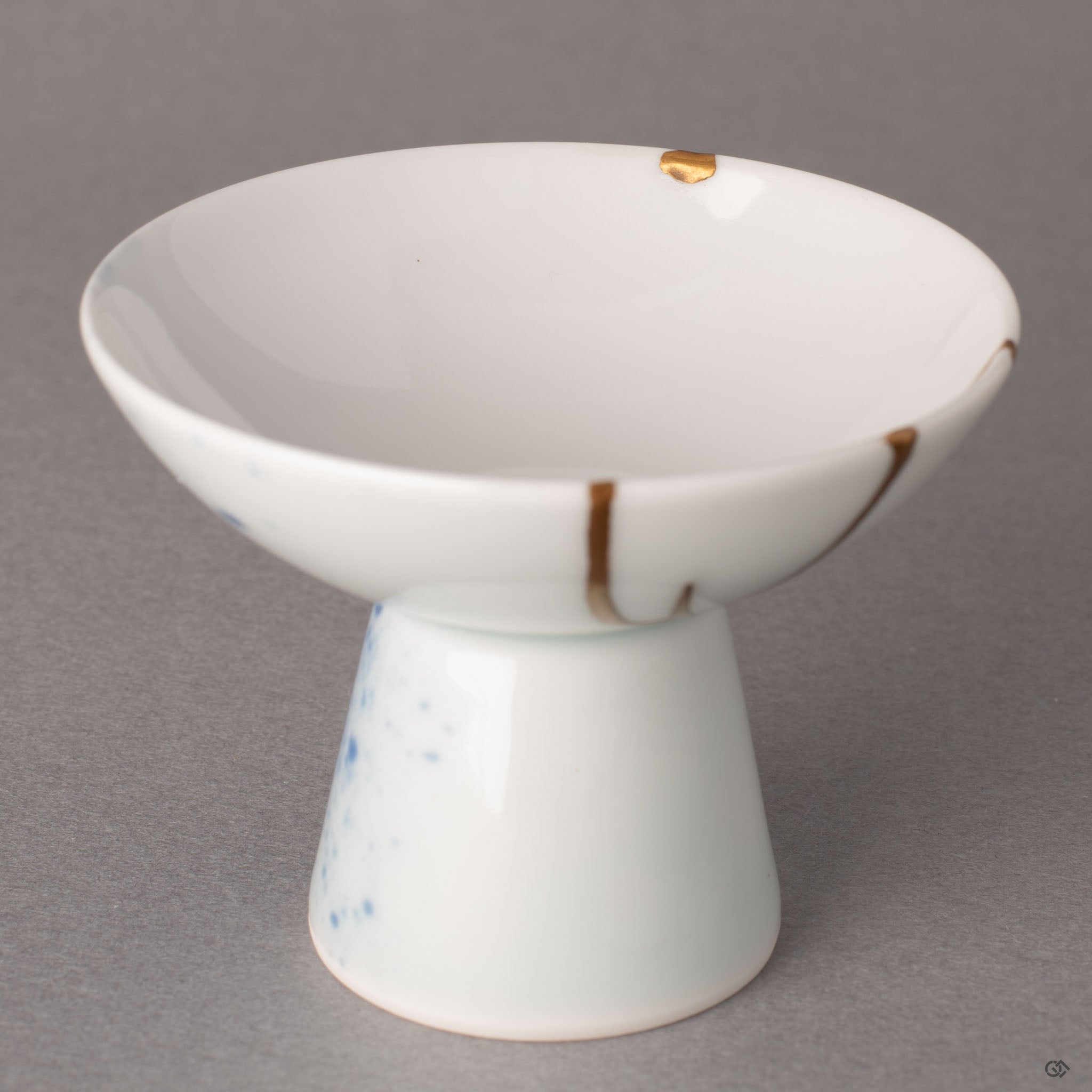 Interior detail of a kintsugi Arita sake cup showing a restored chip finished with 24K gold over urushi lacquer, tactile history in porcelain.