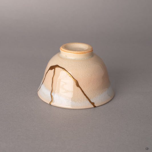 Gold kintsugi seams traverse cream-colored Hagi earthenware, each line a quiet meditation on impermanence.
