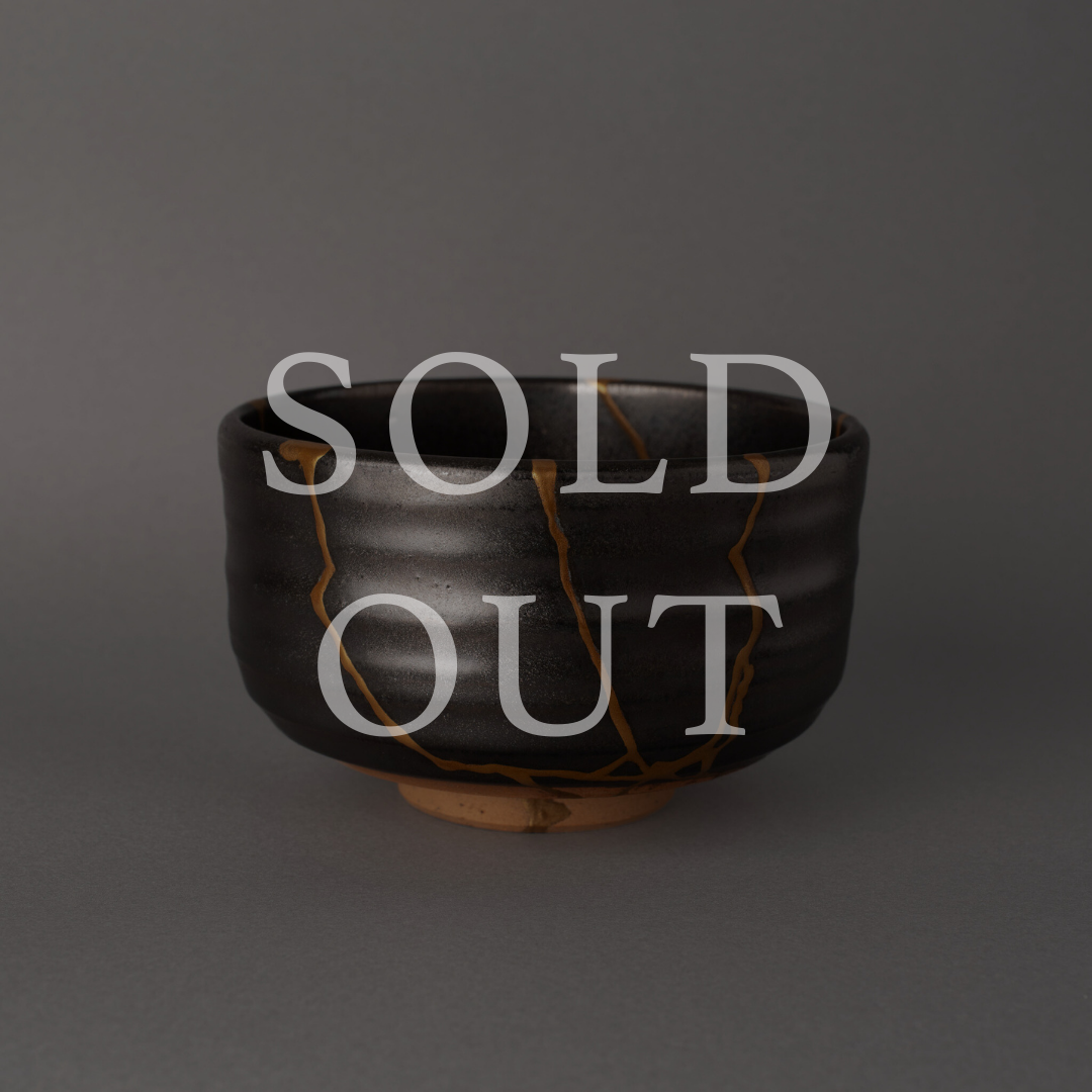 Sold out — Arita-ware black glazed chawan with bold gold kintsugi seams tracing fracture lines across dark ceramic, a wabi-sabi meditation in contrast.