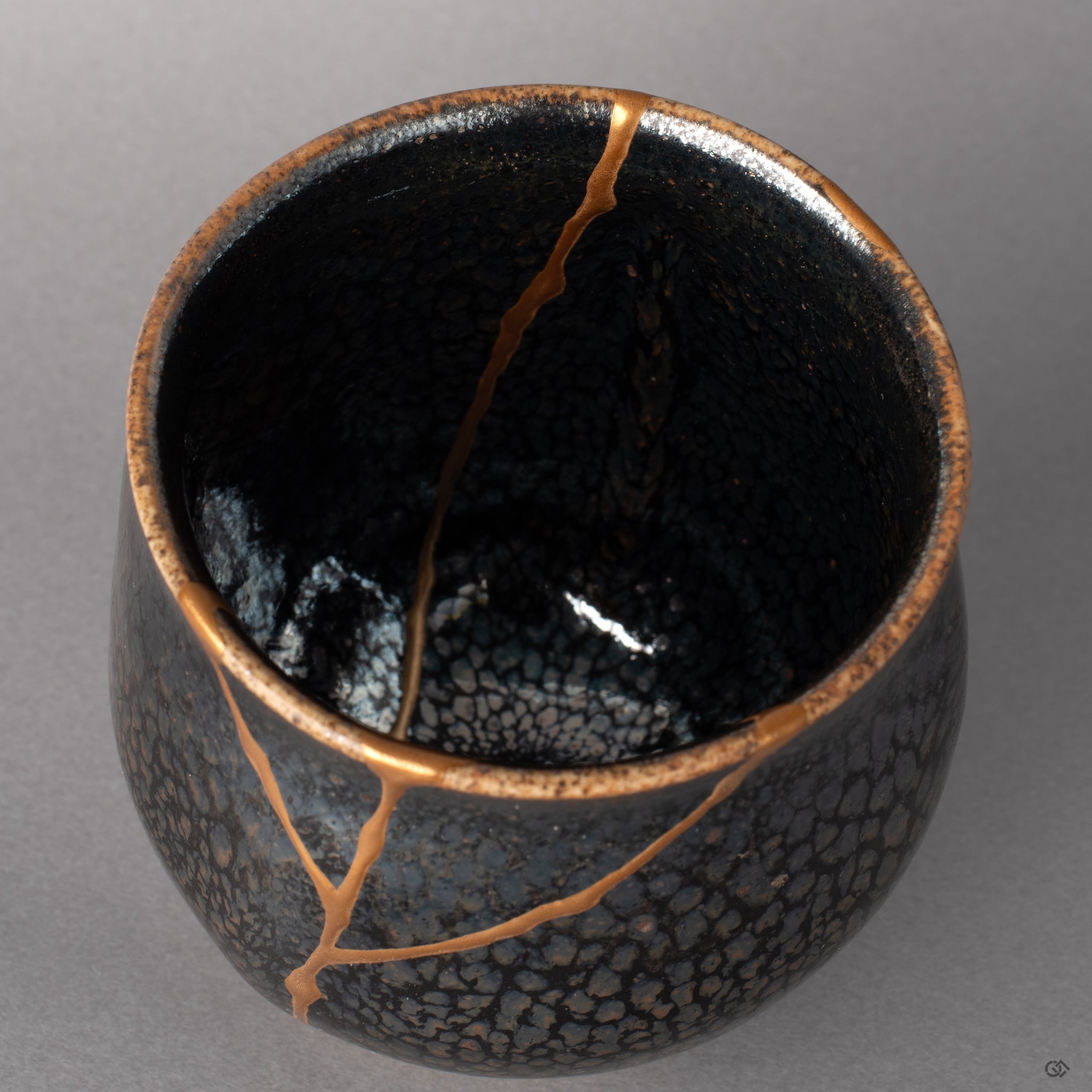 Inside the Kyoto tenmoku cup, urushi warmth underlies the starlit glaze, kintsugi seams glowing with cultural heritage.