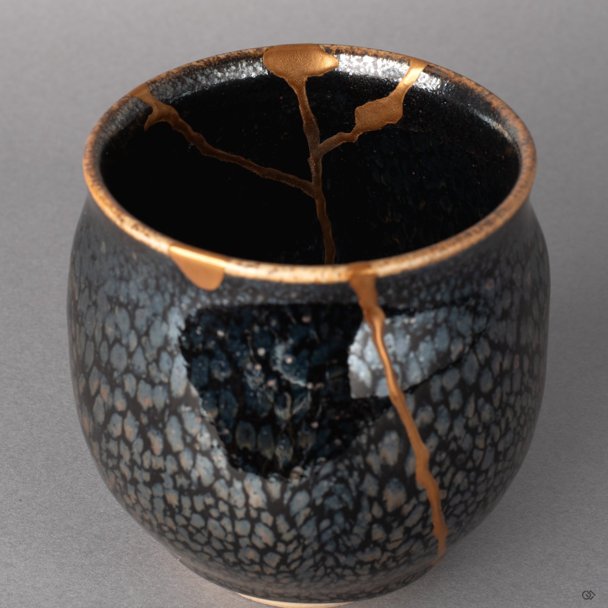 Kintsugi paths wind through this tenmoku interior, gold mapping each mended line, living philosophy held within the cup.