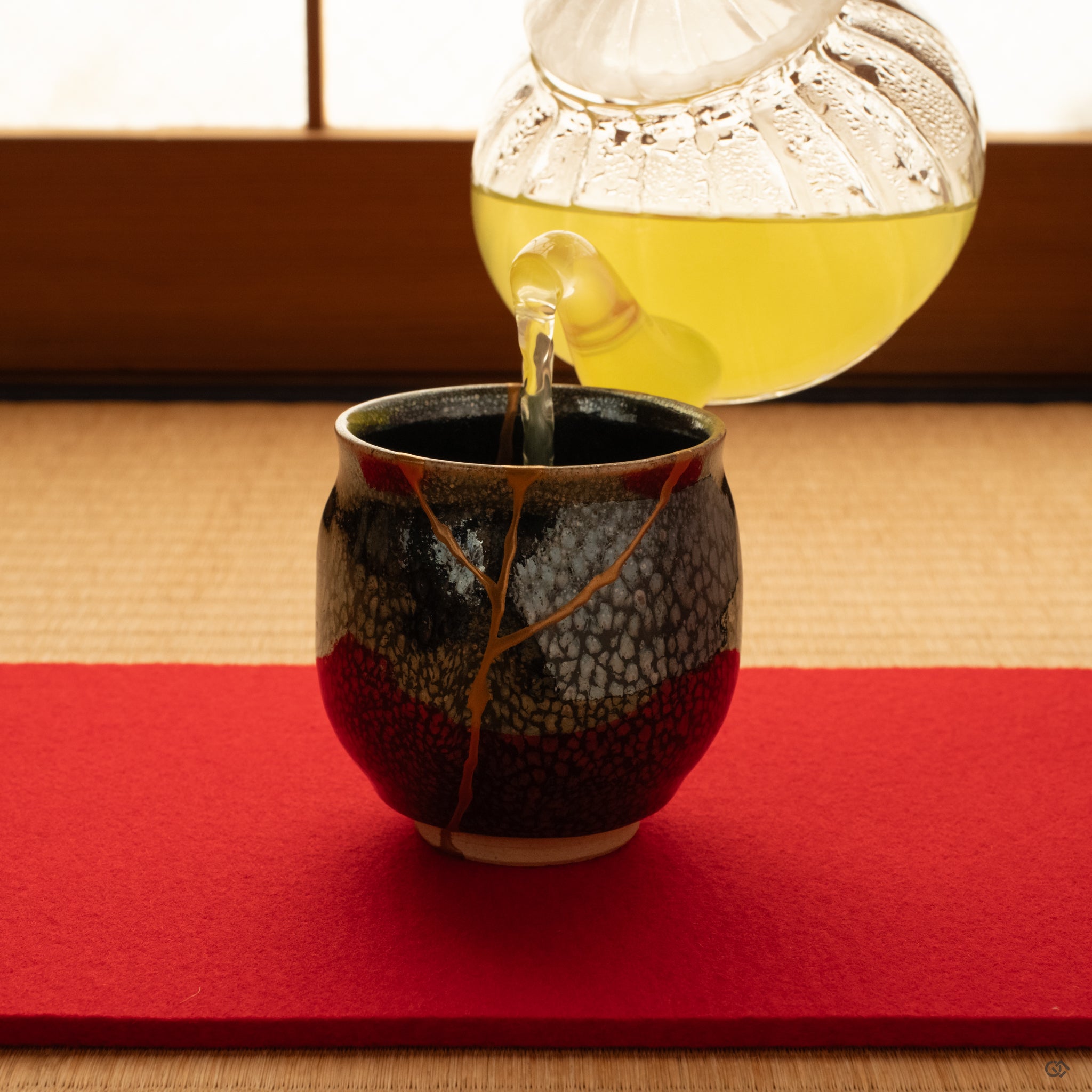 Evening light on tatami as this tenmoku kintsugi cup rests in stillness, silver flecks and gold seams quiet together, slow craft at peace.