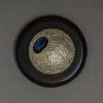 Top view of Keiko Hata's Amamitsuki (Full Moon of the Heavens, 2024) mounted on a round dark wood panel: a textured gold-leaf urushi (Japanese lacquer) moon set with an oval blue raden (mother-of-pearl) window of stars.