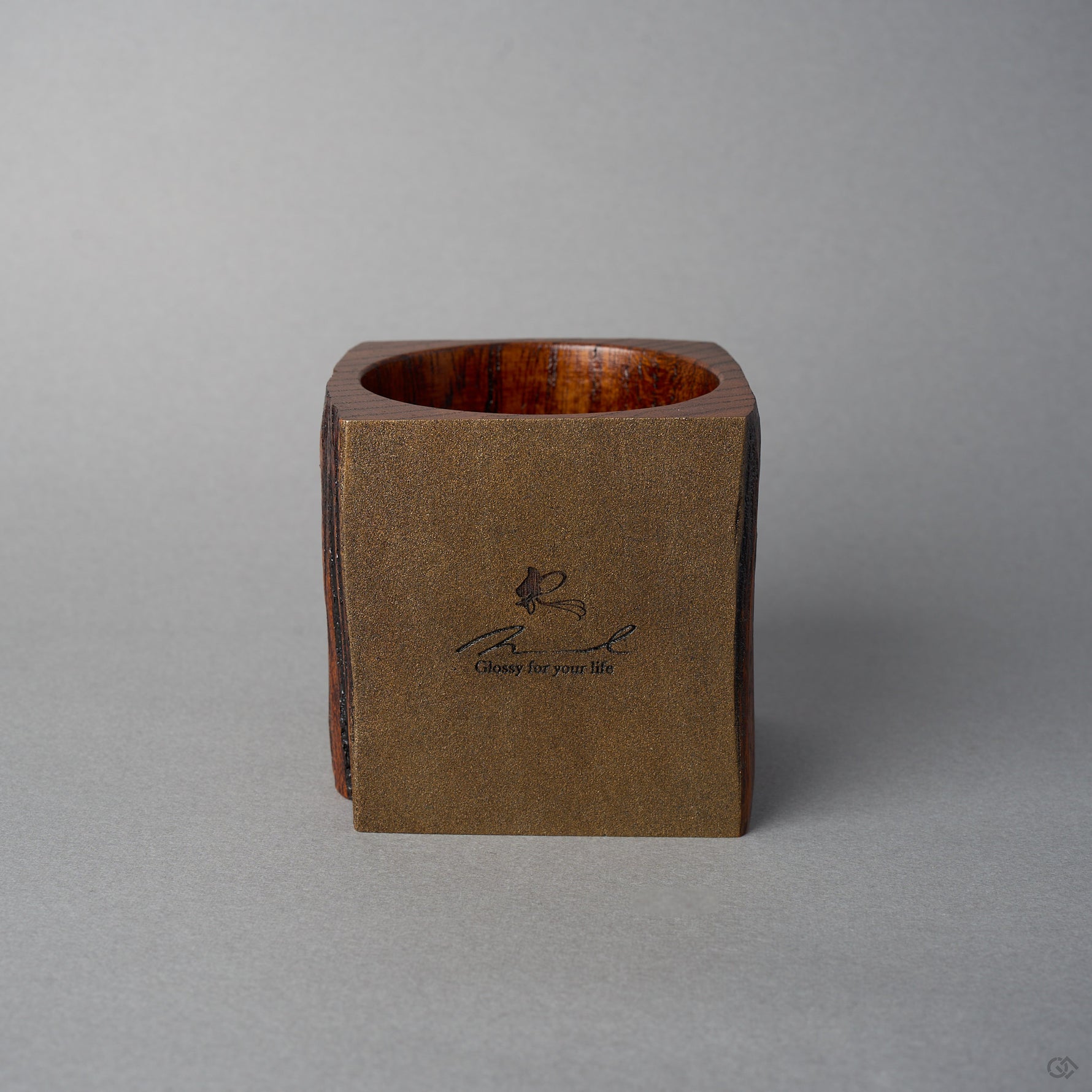 Angled front view of Nobuyasu Suginaka's KODAMA Nashiji : an aged-wood vessel whose front face is finished in metal-flecked nashiji lacquer that shimmers like bronze, bearing a maker's logo.