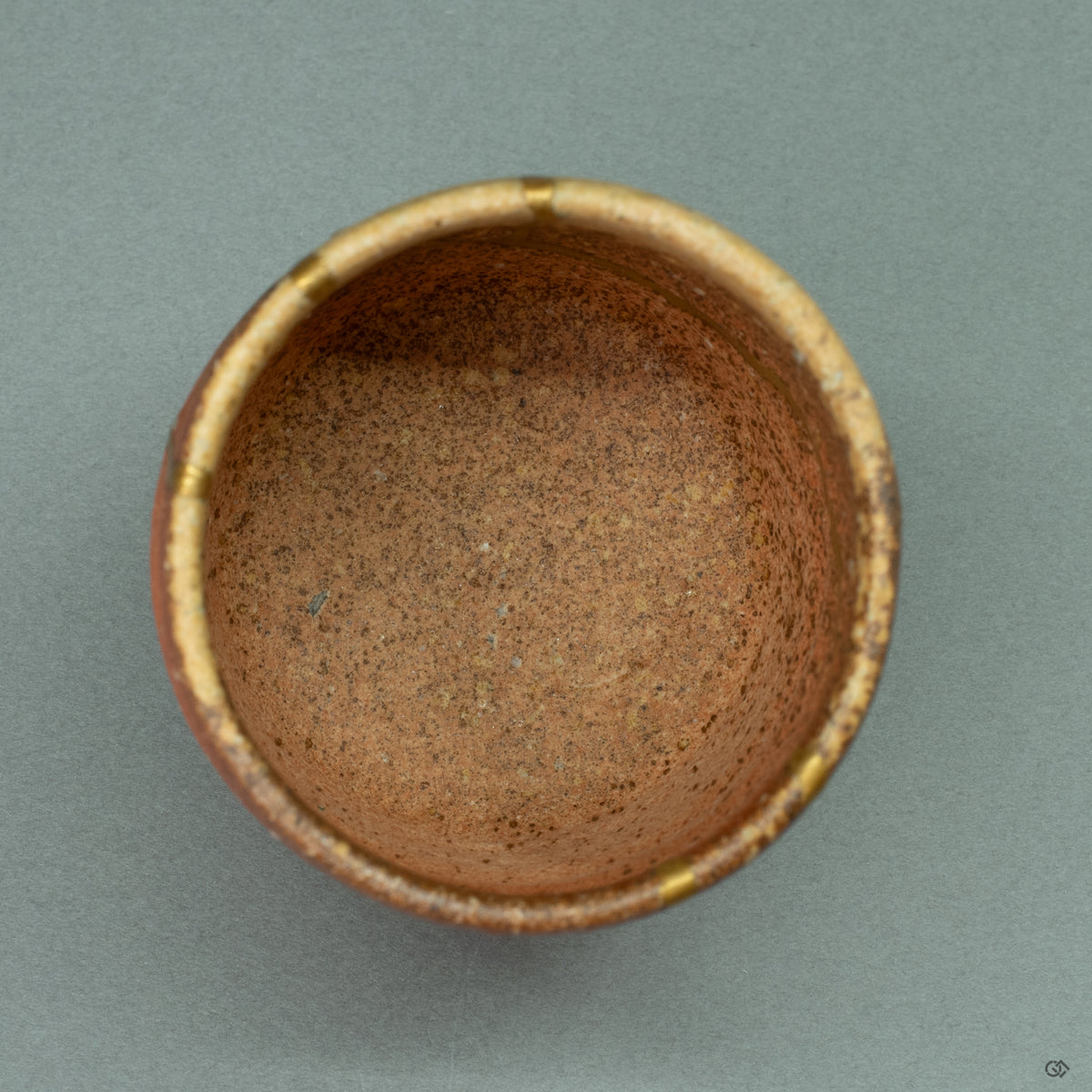 Looking into the Shigaraki tea cup, this top view reveals how the golden Kintsugi repairs continue inside, enhancing the vessel's profound wabi-sabi character.