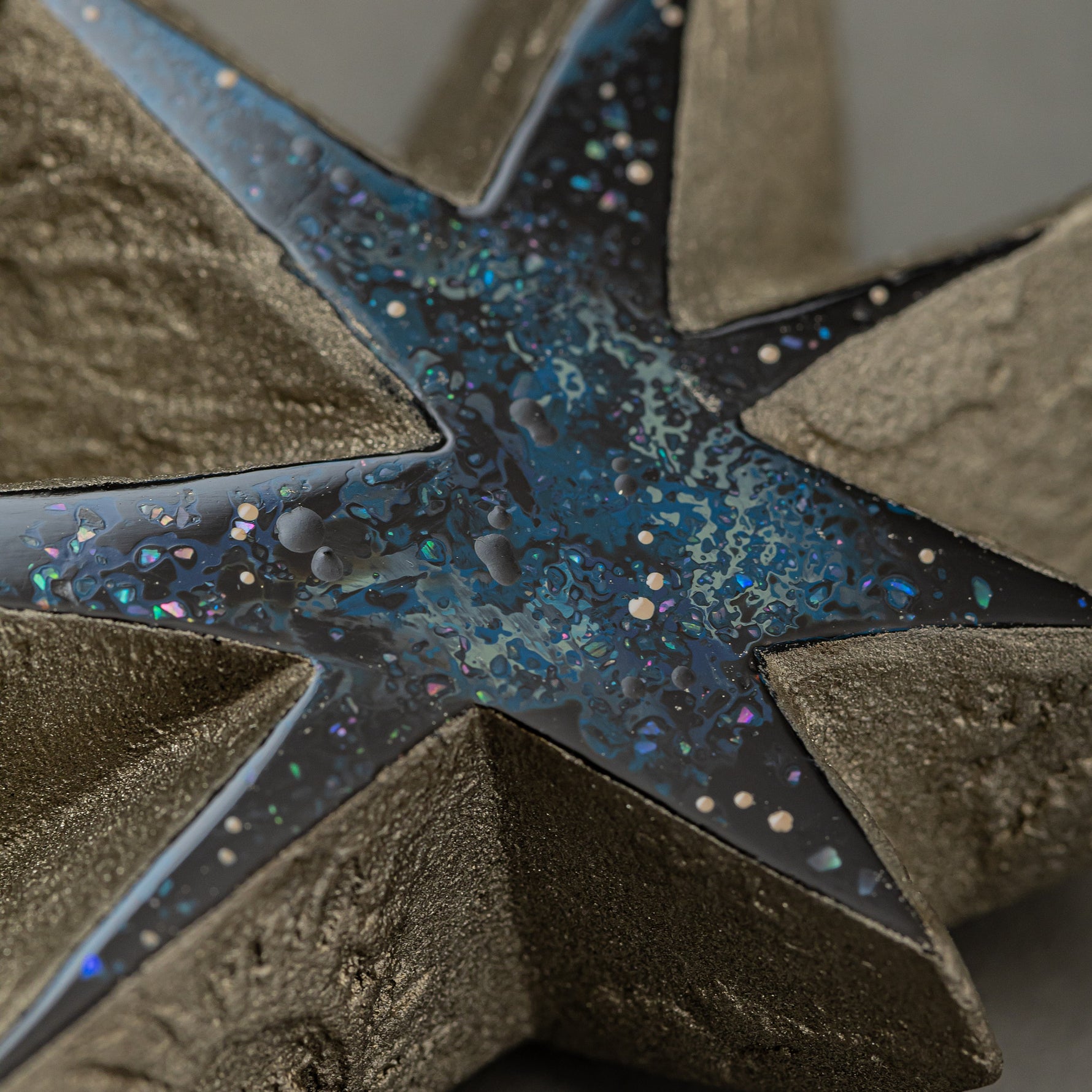 Macro detail of the blue urushi center of Kiraboshi / Hakugin, where raden flecks and tin powder sparkle like scattered stars against the dark lacquer.