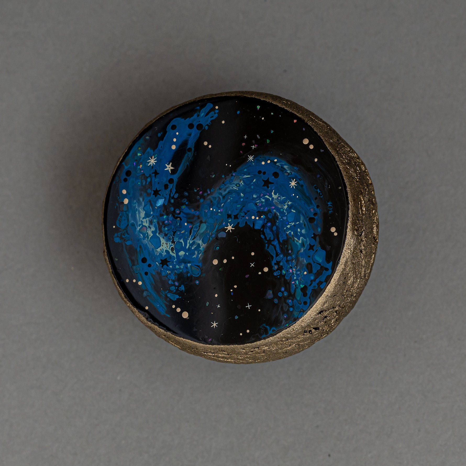 Close view of the domed center of Union of Skies, where blue raden (mother-of-pearl) and iridescent flecks scatter across the black urushi surface.
