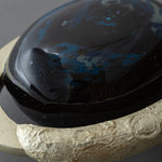 Close view of the domed center of Union of Skies, where blue raden (mother-of-pearl) and iridescent flecks scatter across the black urushi surface.