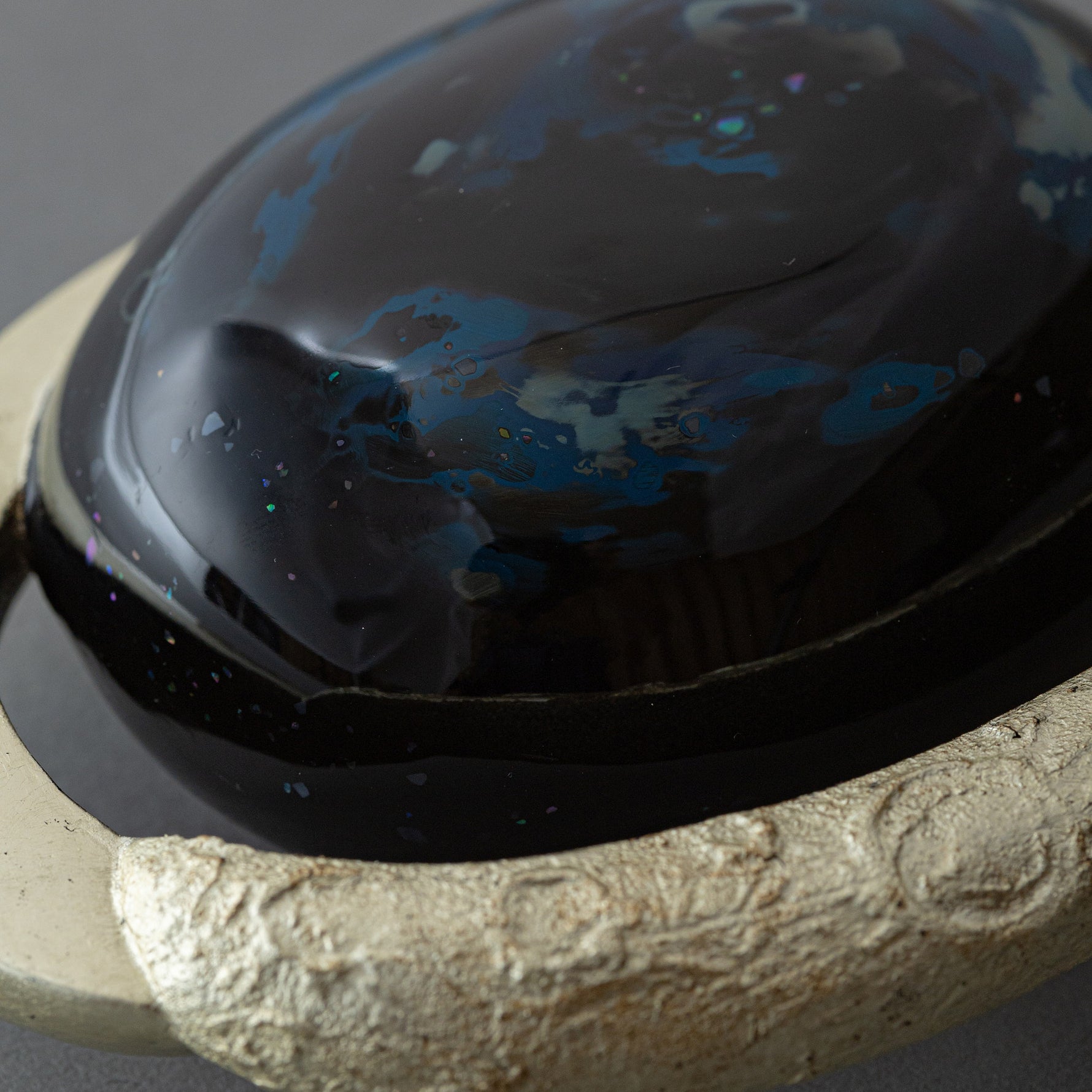 Close view of the domed center of Union of Skies, where blue raden (mother-of-pearl) and iridescent flecks scatter across the black urushi surface.