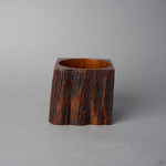 Side view of KODAMA Black Roiro, where the warm reddish-brown grain of the aged wood wraps around the squared body of the vessel.