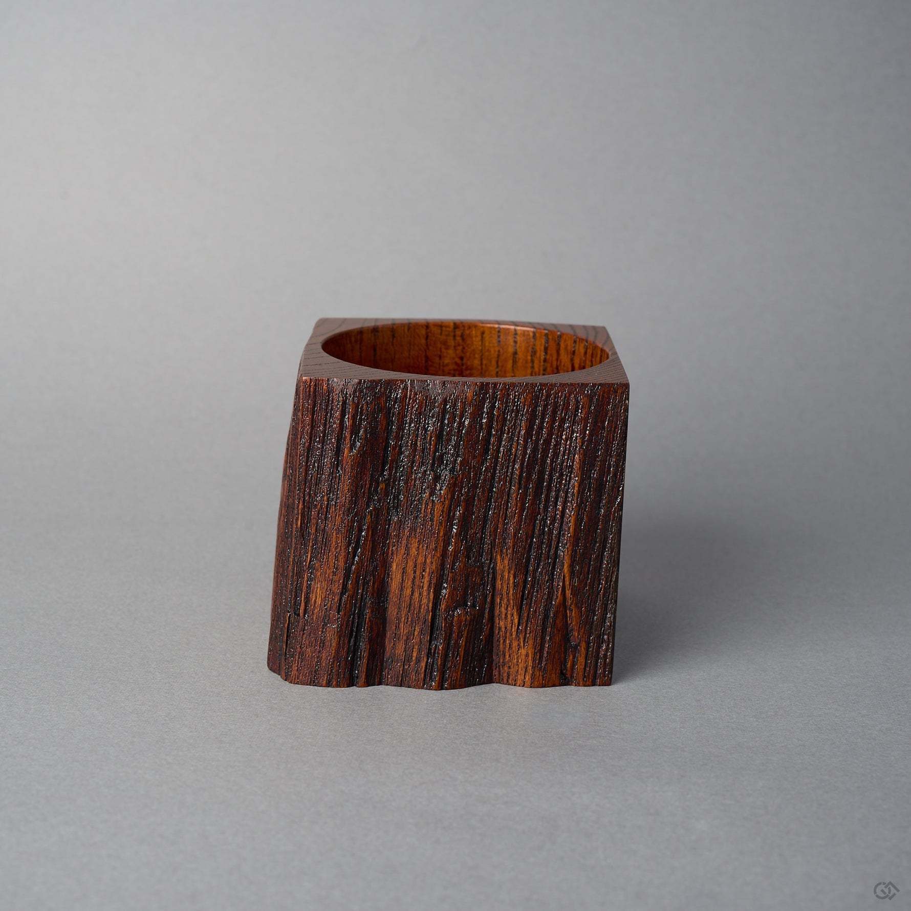 Side view of KODAMA Black Roiro, where the warm reddish-brown grain of the aged wood wraps around the squared body of the vessel.