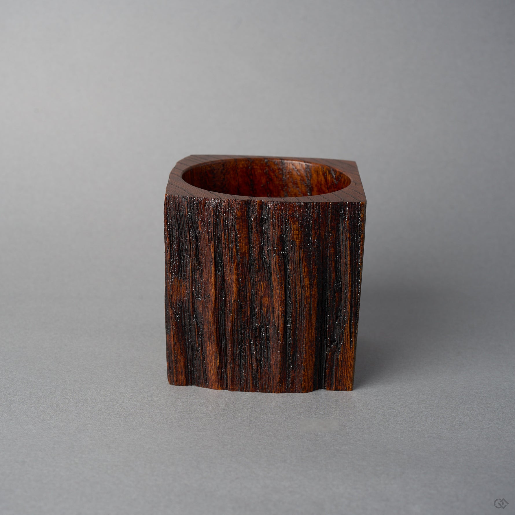 Side view of KODAMA Nashiji, where the dark reddish grain and craggy surface of the aged wood wrap around the carved vessel.