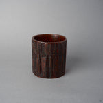 Side view of KODAMA Red Roiro, where the dark reddish-brown grain and craggy surface of the aged wood wrap around the carved form.
