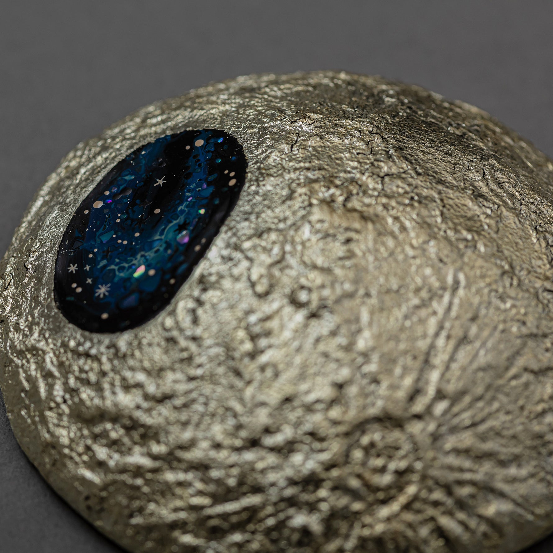 Close view of the carved, cratered gold-leaf surface of Amamitsuki beside its star-filled blue raden window, revealing the layered urushi texture.