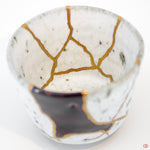 Close-up photo of an authentic Kintsugi pottery piece, showing the detail of its repairs and craftsmanship