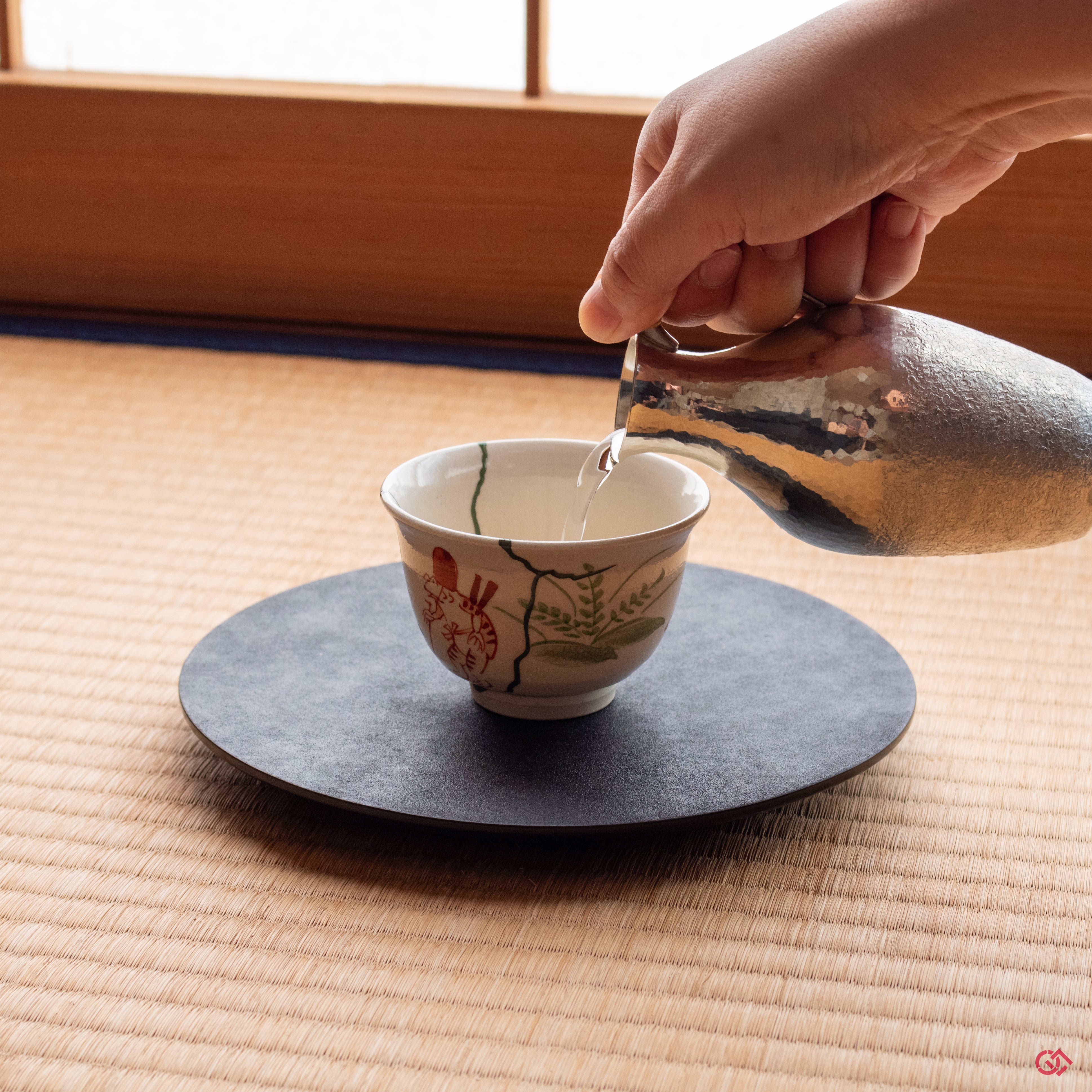 Photo of an authentic Kintsugi pottery piece being used in a real-world setting, such as a cup of sake being poured into a Kintsugi cup.