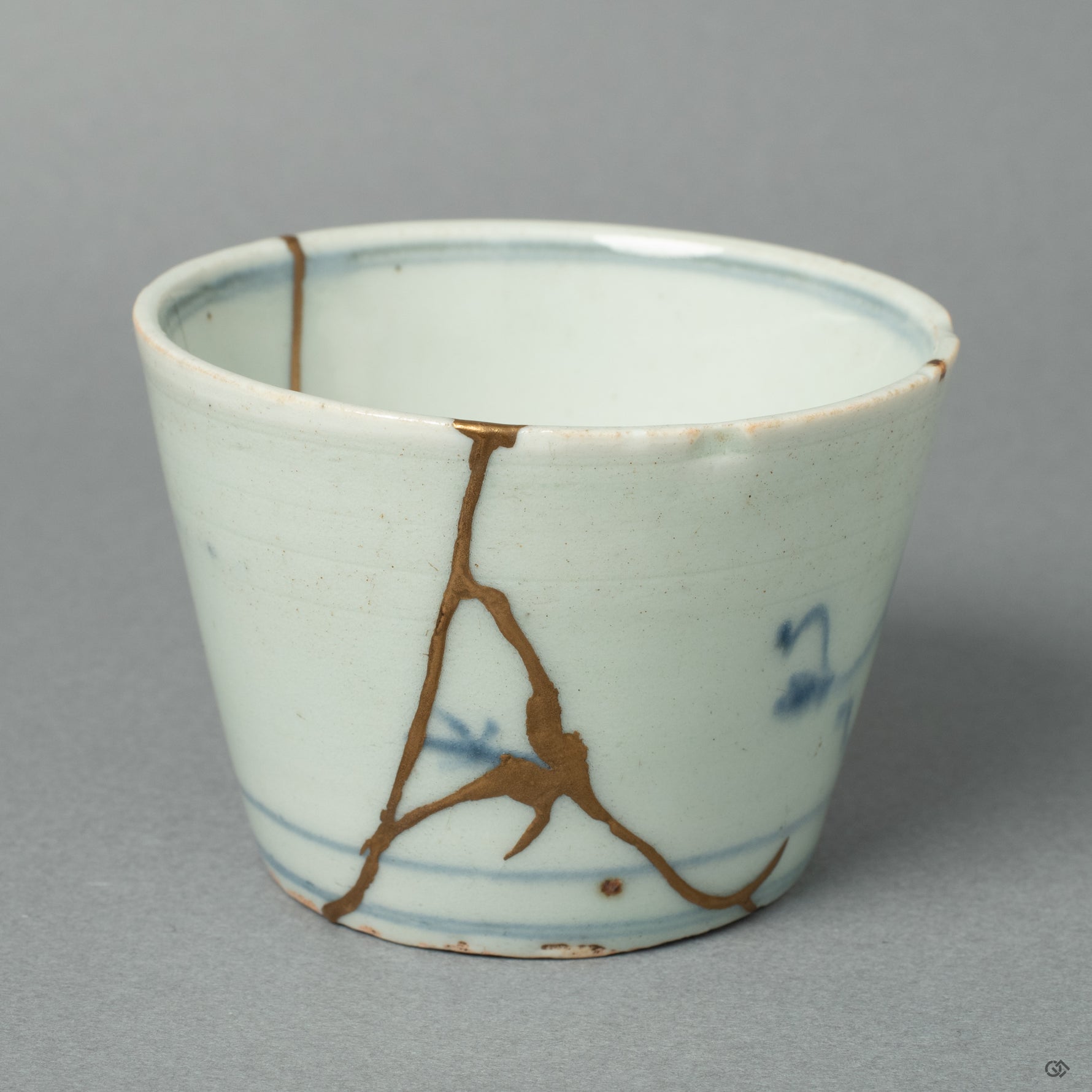 An antique Ko-Imari porcelain ochoko, its historic form reborn with 24k gold Kintsugi by a conservator of sacred Buddhist art. The repair respects the vessel's heritage while adding a new, precious history.