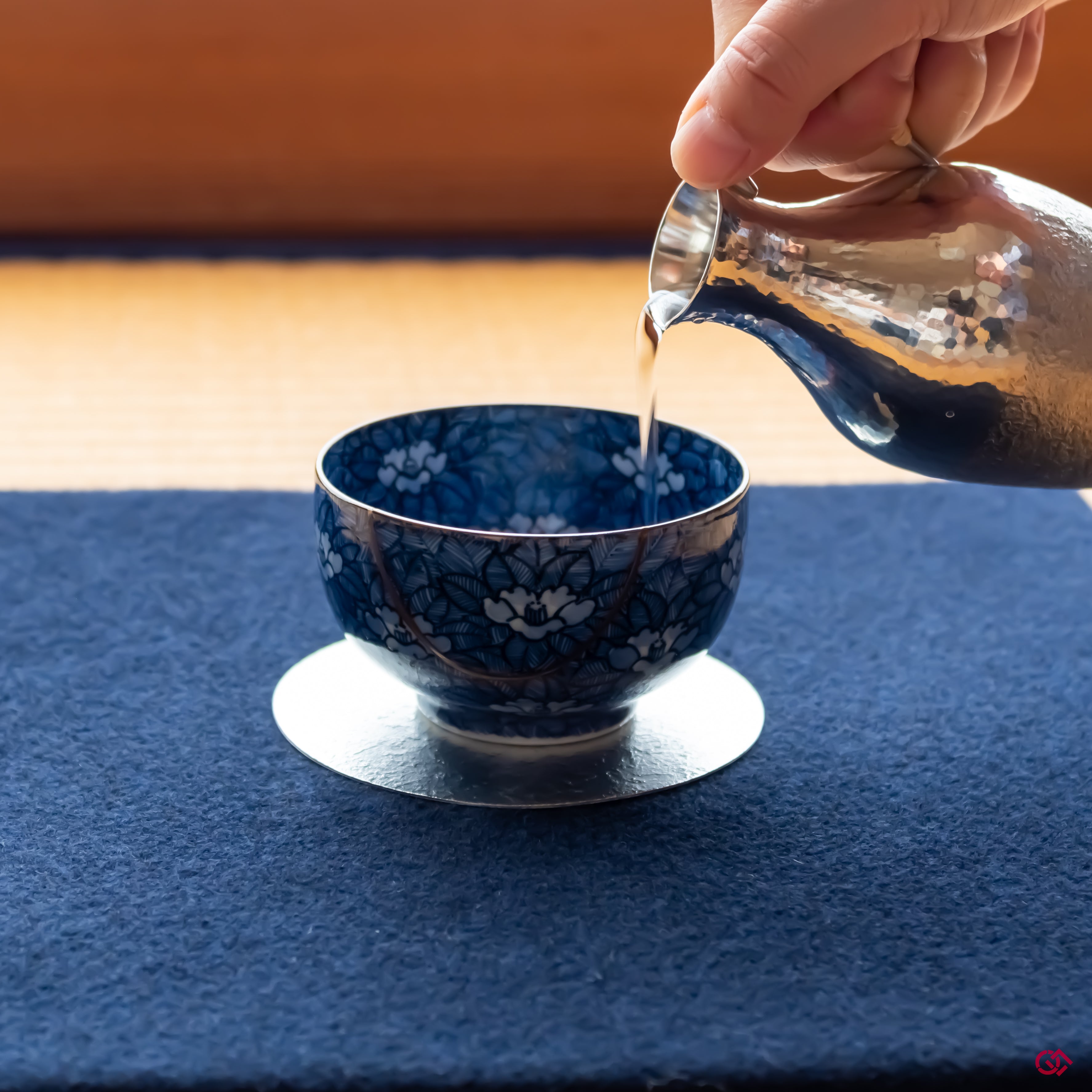 Photo of an authentic Kintsugi pottery piece being used in a real-world setting, such as a cup of sake being poured into a Kintsugi cup