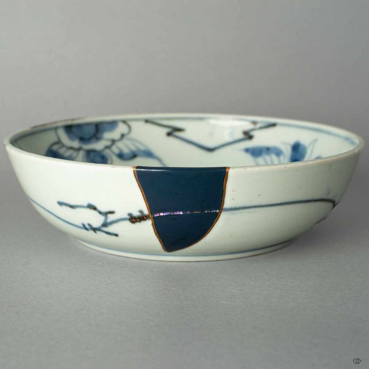 A close-up on the precise point where a 24k gold Kintsugi seam meets the iridescent shimmer of a Raden mother-of-pearl inlay.