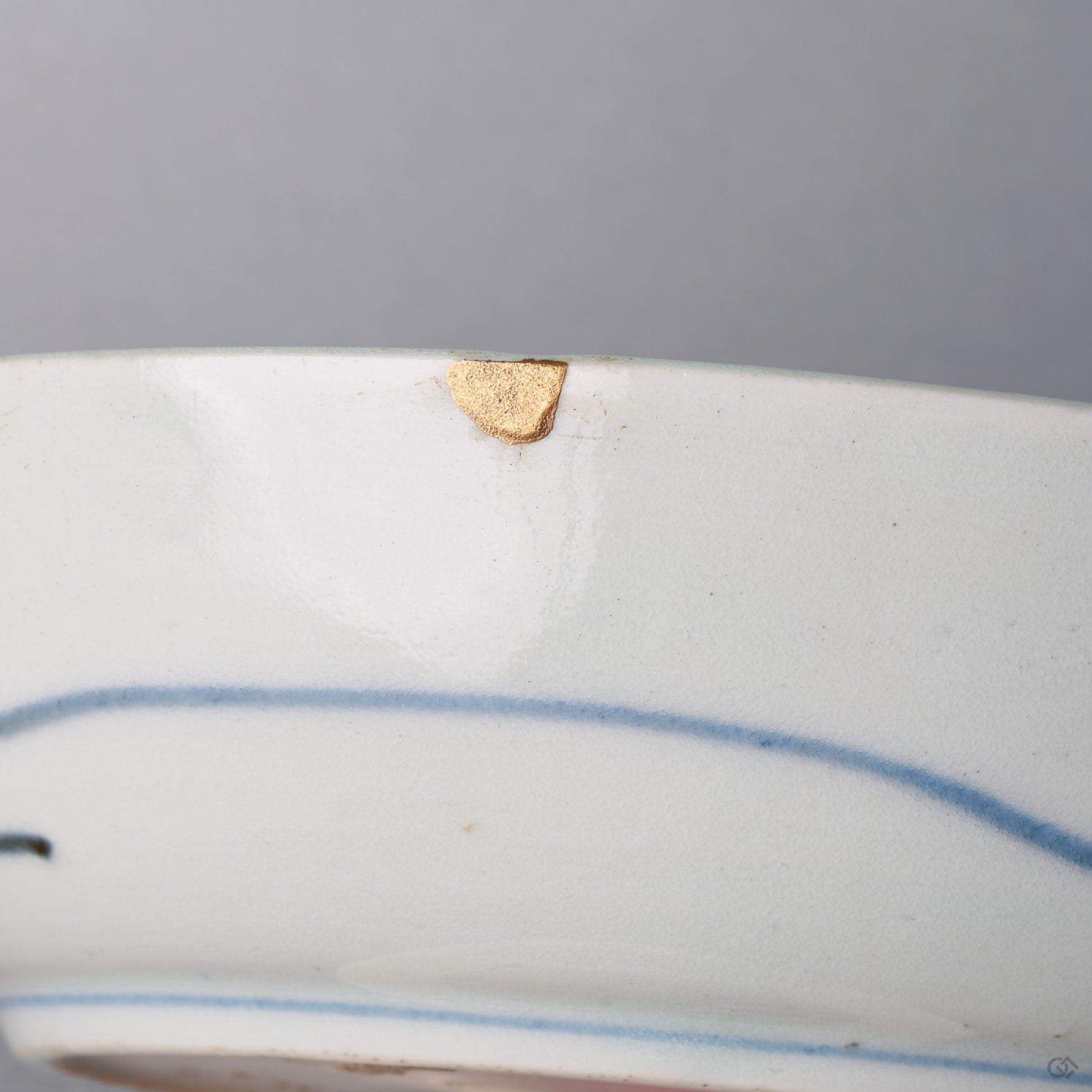 Close-up of a small chip on the outer rim of a Ko-Imari bowl, restored with natural urushi kintsugi and finished in softly lustrous 24K gold.