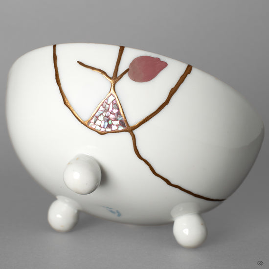 A macro view of the urushi-e and raden inlay on the porcelain. There is a 'story in every seam, a narrative of rebirth told in urushi lacquer and gold.