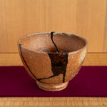 The unique mixed-media kintsugi cup put on the tatami, offering a moment of connection with its complex past and renewed, artistic present.