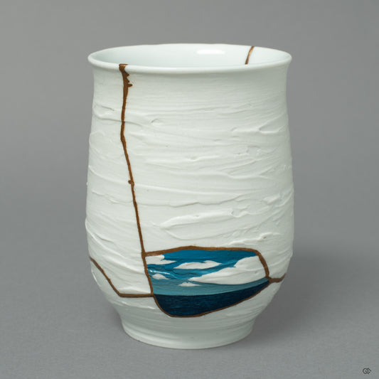A Nabeshima ware cup, where 24k gold Kintsugi meets a blue Urushi-e painting of the sea and sky, a horizon of art on white porcelain.