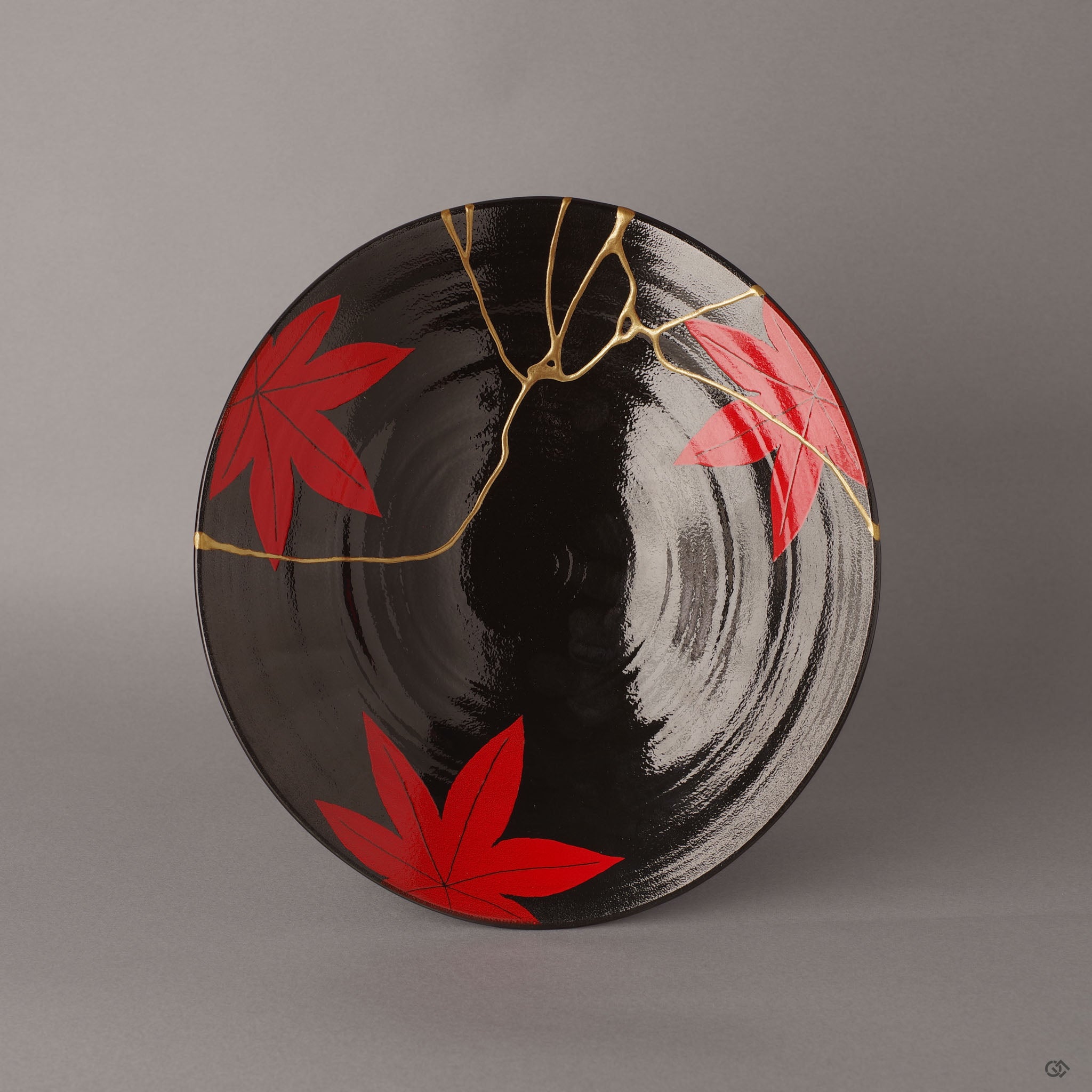 A top-down view of an Arita ware bowl, its black glaze a canvas for the dialogue between crimson maple leaves and radiant 24K gold kintsugi repair.