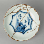A top-down view into a Ko-Imari bowl, revealing the path of its gold and iro-urushi kintsugi repair, a quiet meditation on beauty in imperfection.