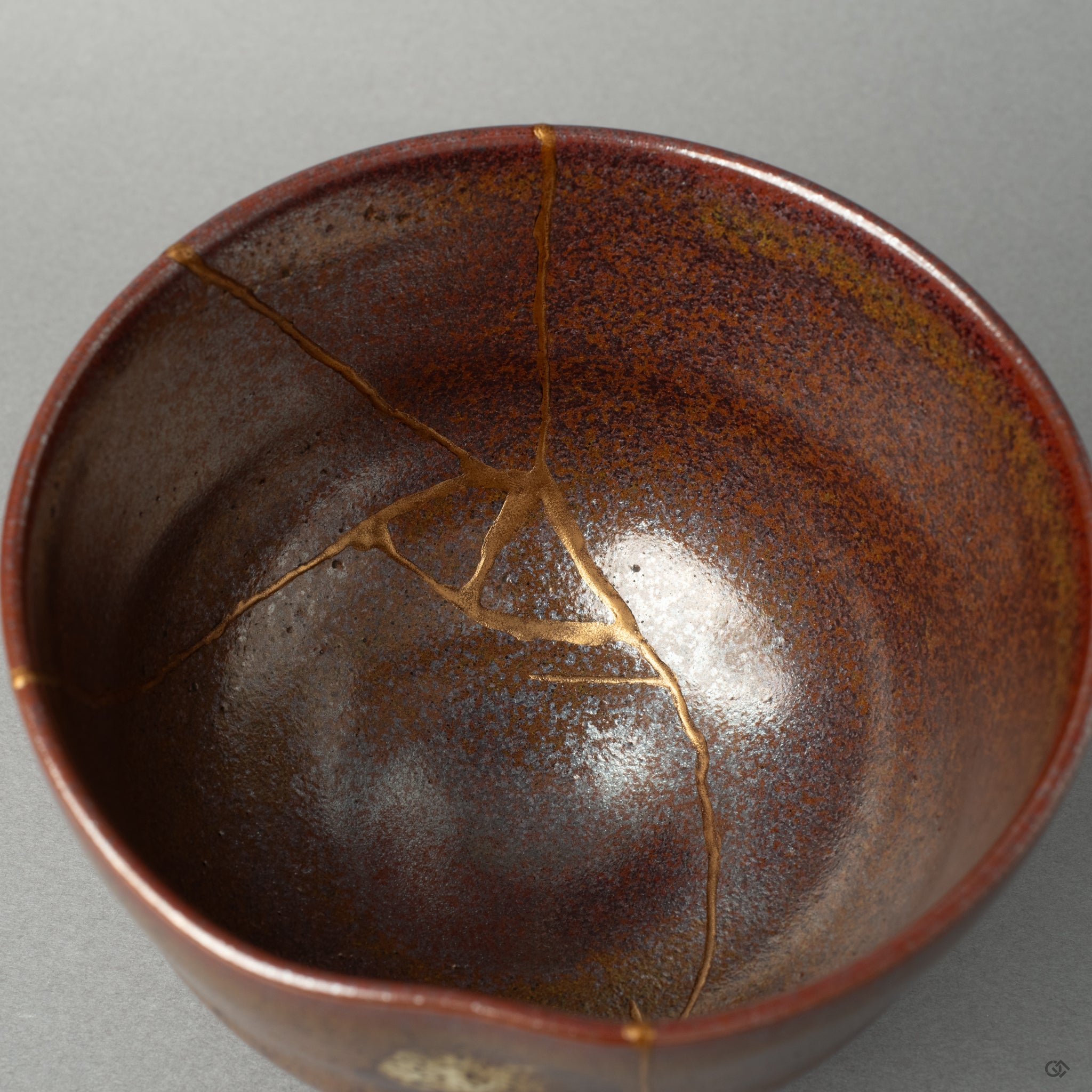 A close-up of the bowls interior, where the precise golden joinery of the kintsugi repair shines against the ceramic glaze.