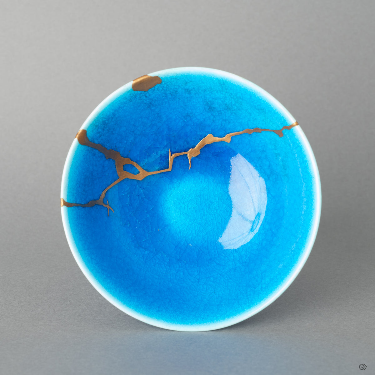 Top-down view of a kintsugi sake cup, its golden joinery tracing a history made visible—a tangible piece of Japanese philosophy.