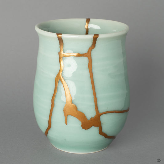 A front view of the authentic Nabeshima ware tea cup, its elegant celadon glaze graced by the quiet beauty of a 24k gold Kintsugi repair.