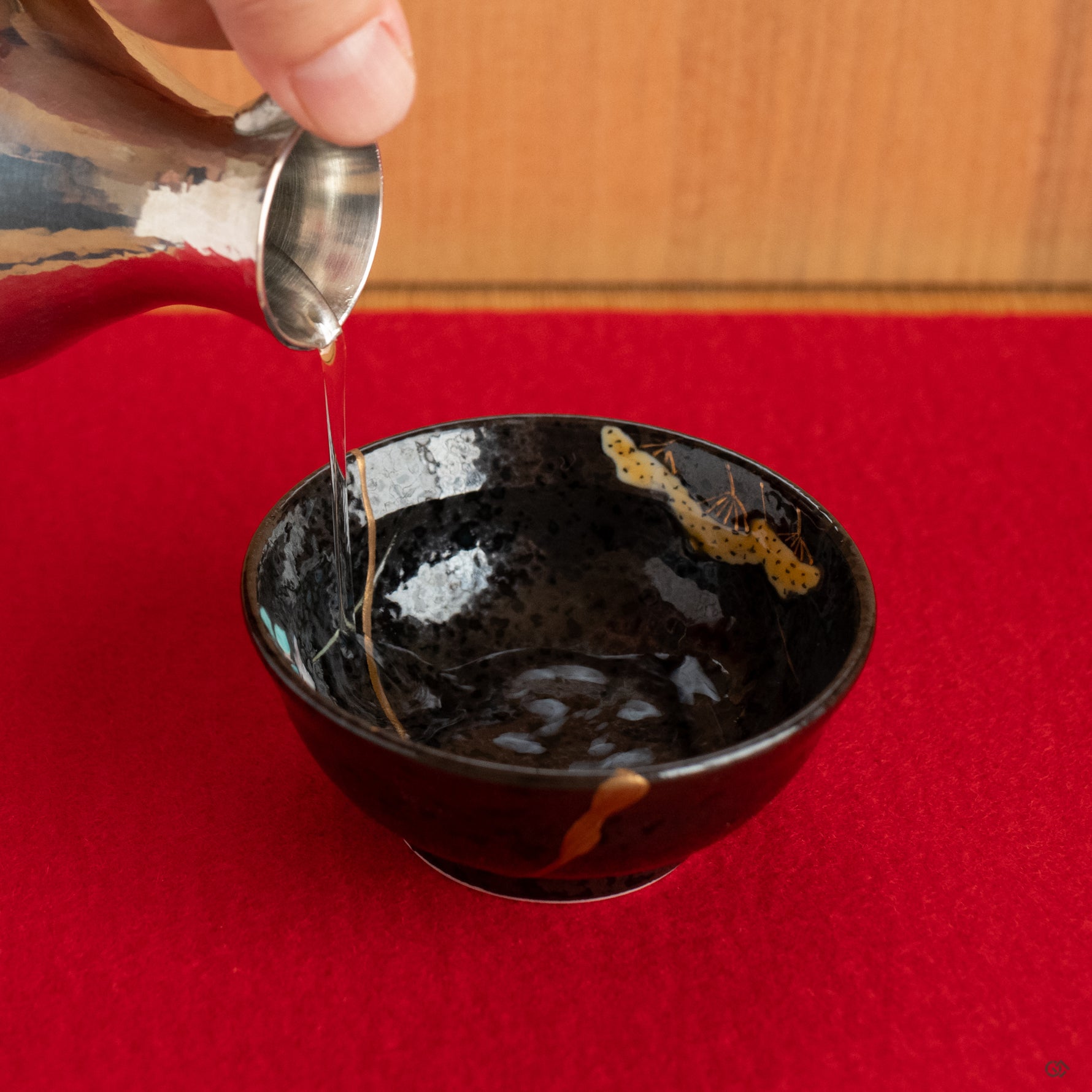 The kintsugi Arita cup, put on the red color felt for puring a sip of sake, a restored and soulful object that enriches the moment.