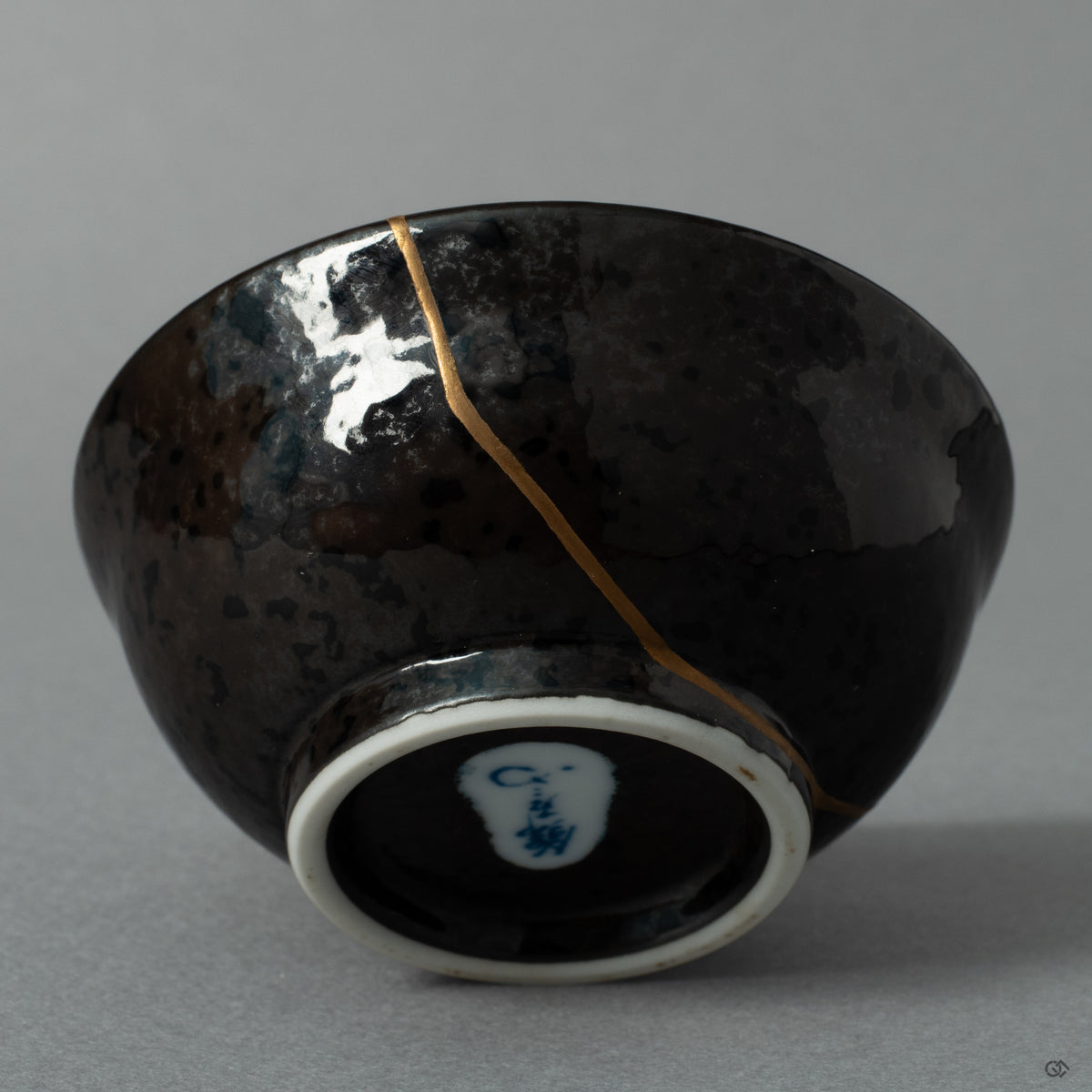 The shining 24K gold kintsugi seam on the ceramic surface, a quiet moment where the vessels journey becomes history made visible.