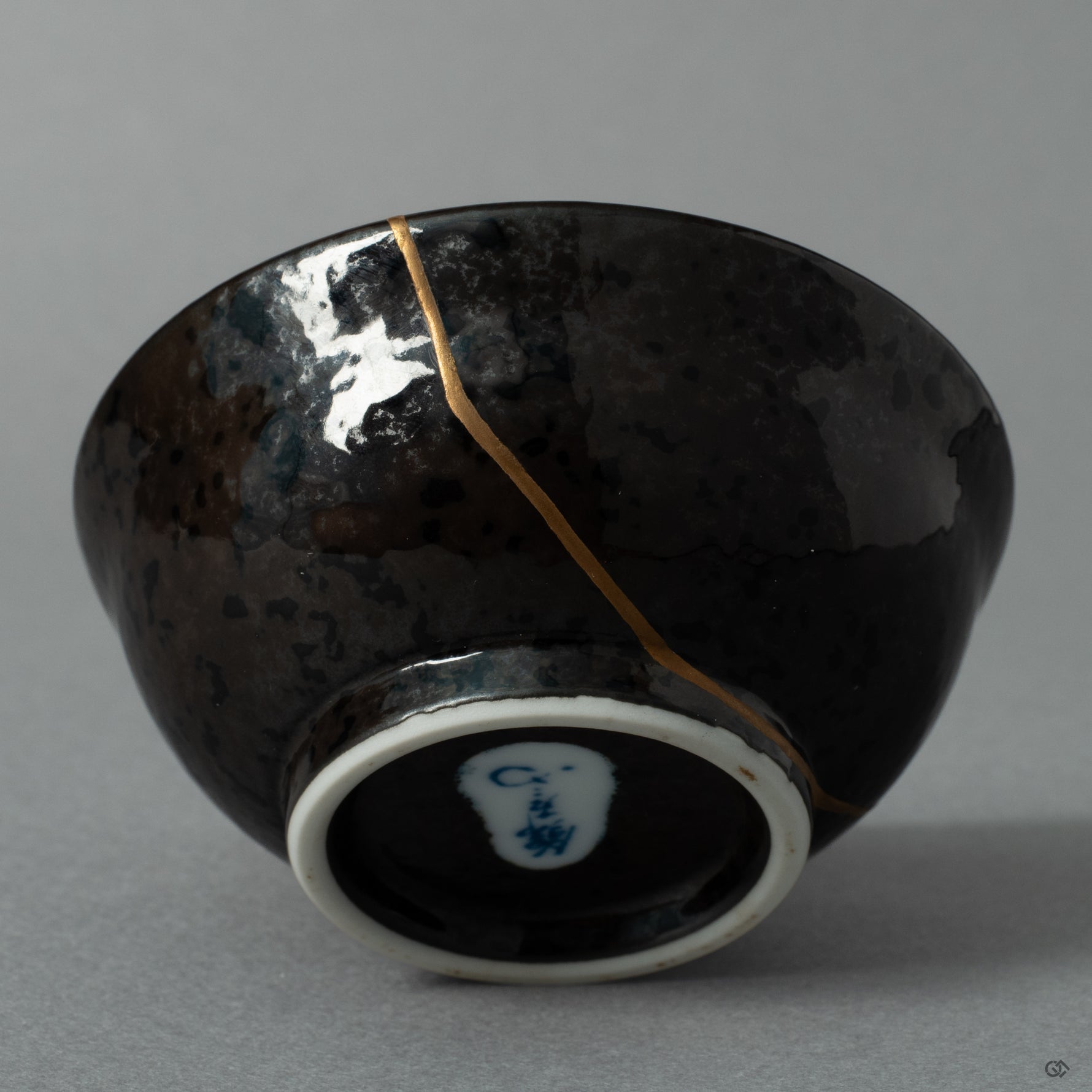 The shining 24K gold kintsugi seam on the ceramic surface, a quiet moment where the vessels journey becomes history made visible.