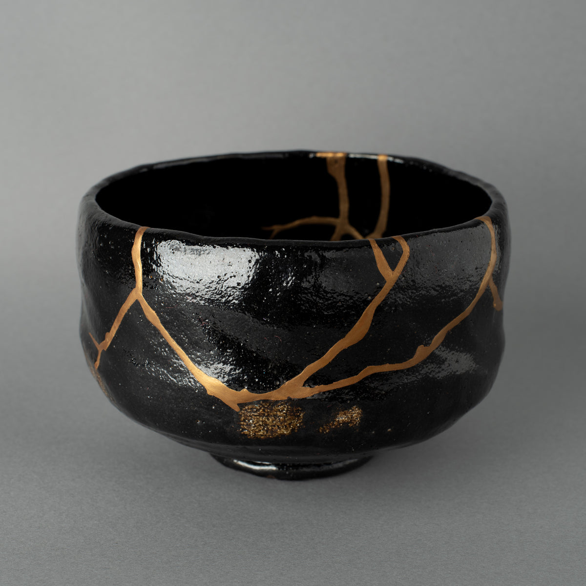 Black Japanese matcha bowl after authentic kintsugi restoration with natural urushi and 24K gold in Japan.