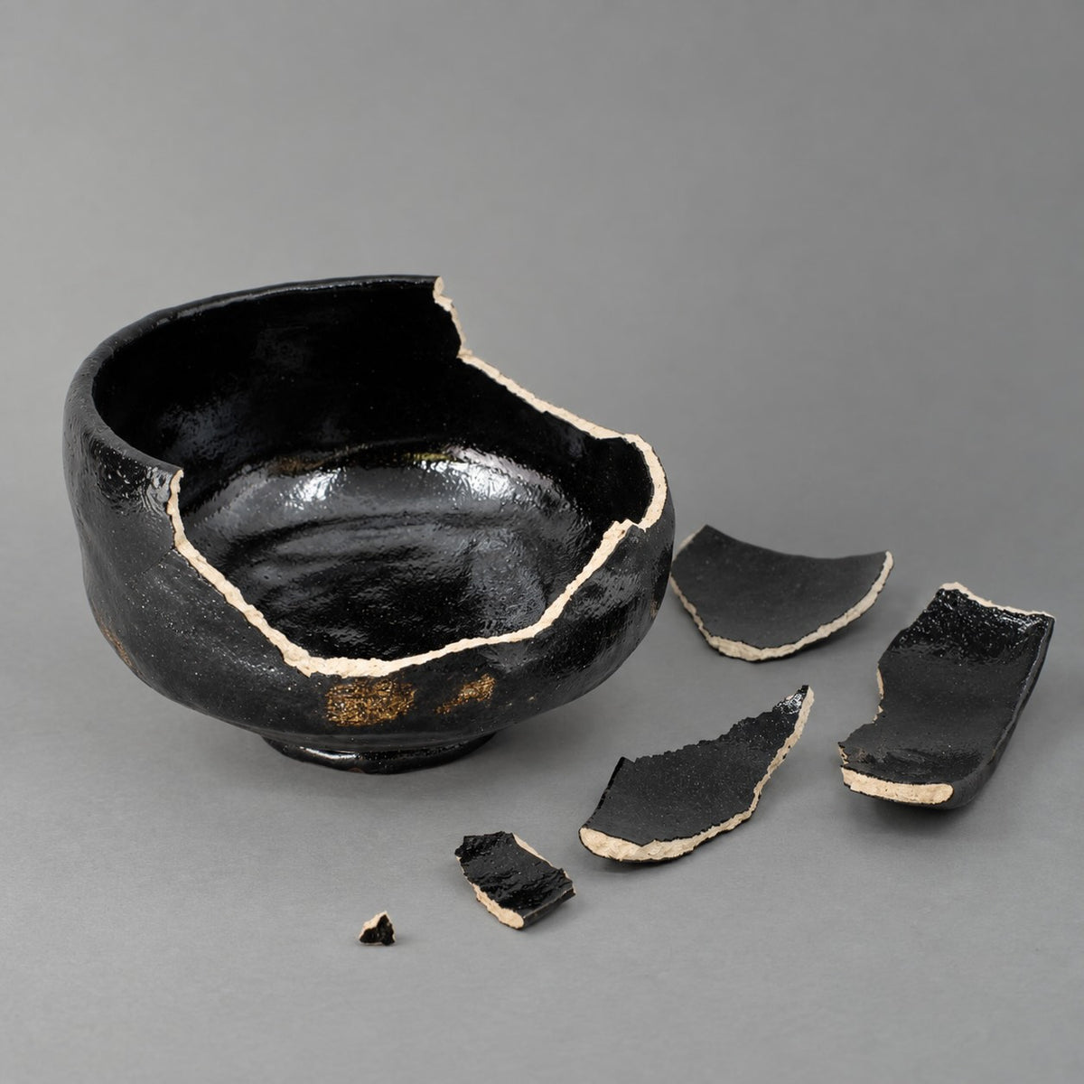 Broken black Japanese matcha bowl before authentic kintsugi restoration with natural urushi in Japan.