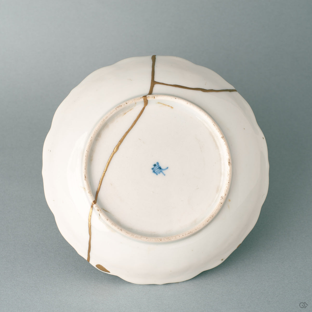 The base of a Ko-Imari kintsugi bowl in white porcelain, where slow craft and a foliate rim reveal its export-ware origins.