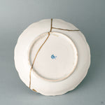 The base of a Ko-Imari kintsugi bowl in white porcelain, where slow craft and a foliate rim reveal its export-ware origins.