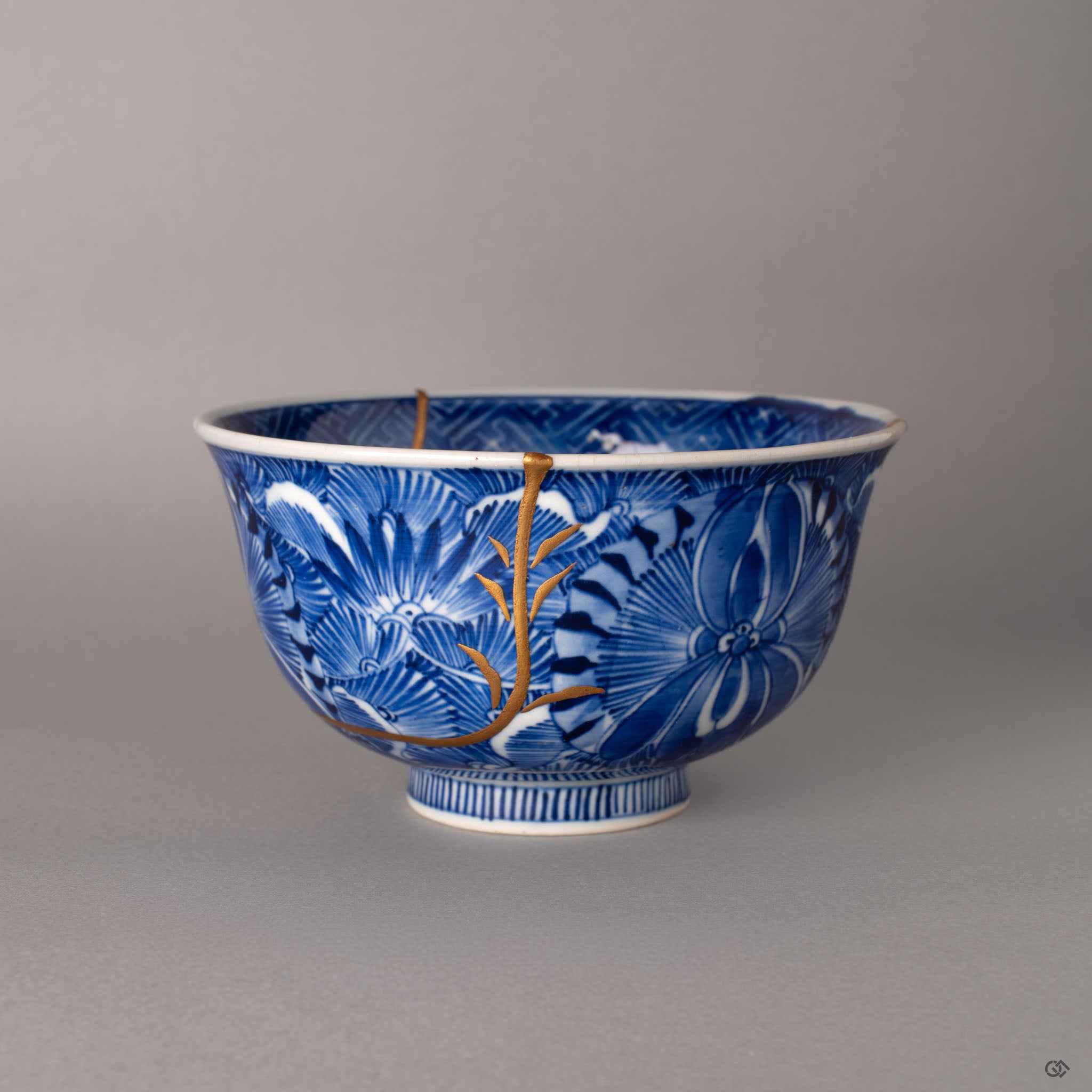 Ko-Imari kintsugi bowl with sometsuke botanicals and gold maki-e branches, front view on grey background, a tangible piece of Japanese philosophy.