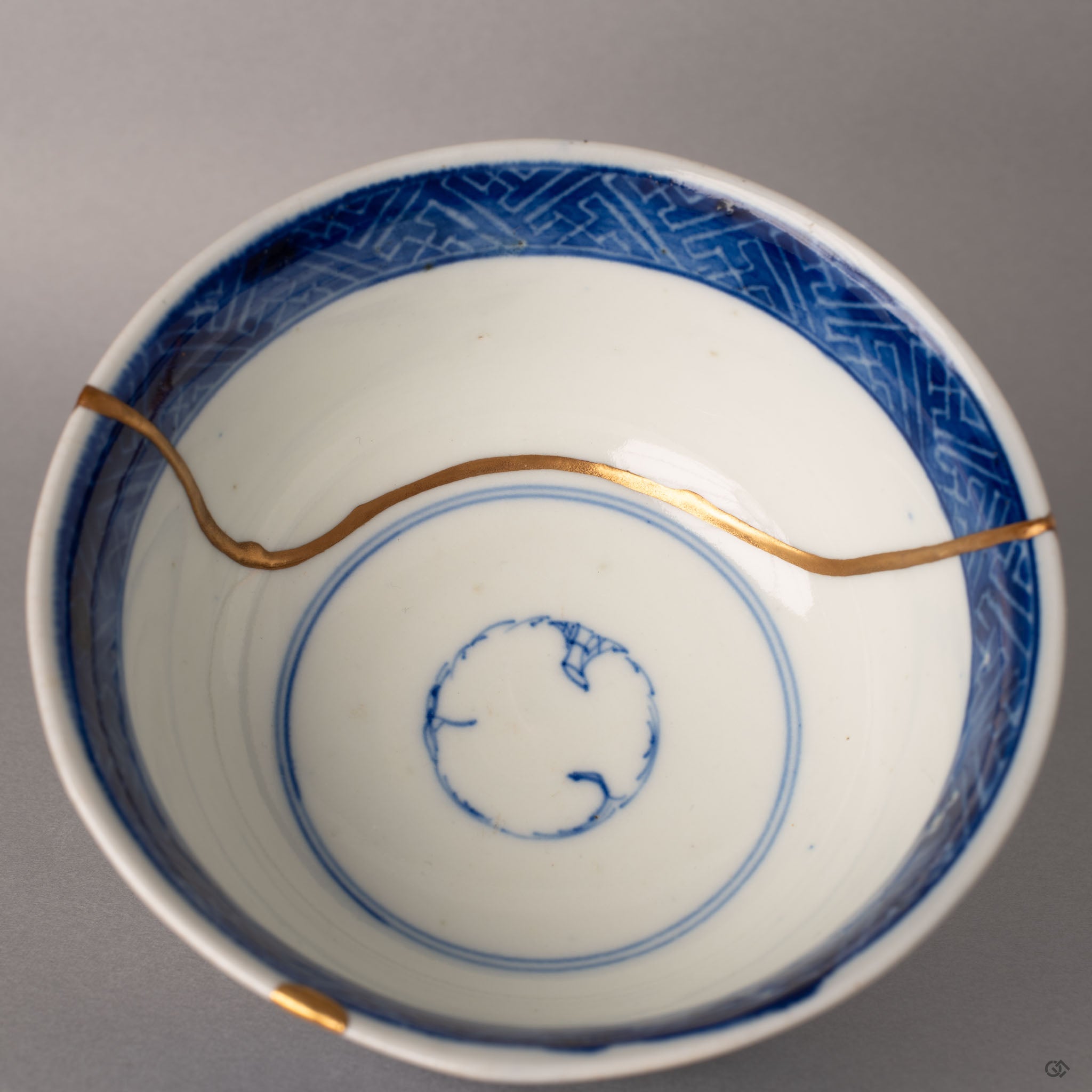 Interior of a Ko-Imari kintsugi bowl with diamond-pattern band and gold seams over sometsuke blue glaze, history made visible.