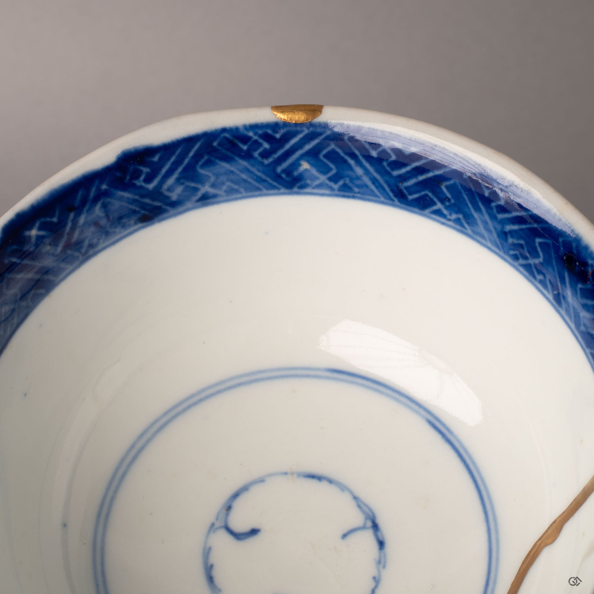 Interior close-up of chip restoration on a Ko-Imari kintsugi bowl rim, gold urushi finish against cobalt blue, enduring legacy.