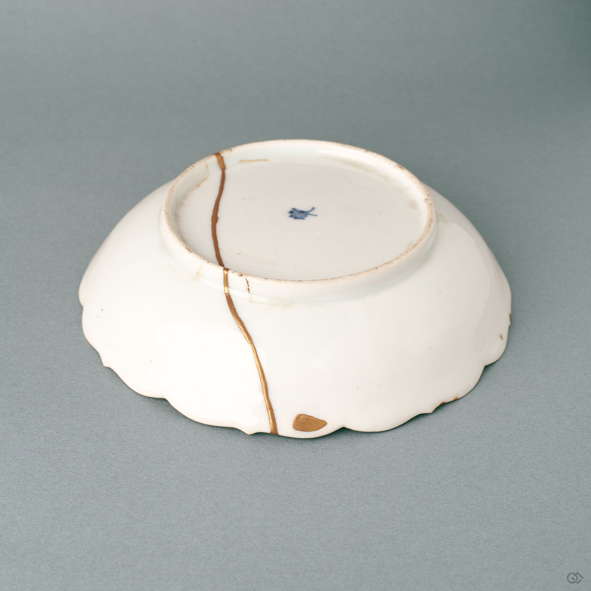 Side profile of a shallow kintsugi Ko-Imari bowl, its gold-edged foliate rim carrying a wabi-sabi calm.