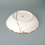 Side profile of a shallow kintsugi Ko-Imari bowl, its gold-edged foliate rim carrying a wabi-sabi calm.