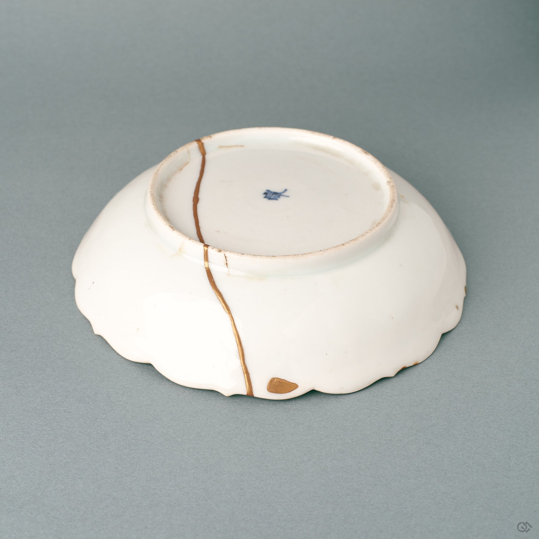Side profile of a shallow kintsugi Ko-Imari bowl, its gold-edged foliate rim carrying a wabi-sabi calm.