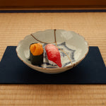 A kintsugi Ko-Imari bowl on tatami, soft light across its gold seam and cobalt landscape, an unhurried moment of conscious luxury.