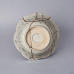 Underside of a Ko-Imari kintsugi bowl, unglazed foot ring and blue lattice motifs crossed by pure silver kintsugi seams, restored with natural urushi in Japan.