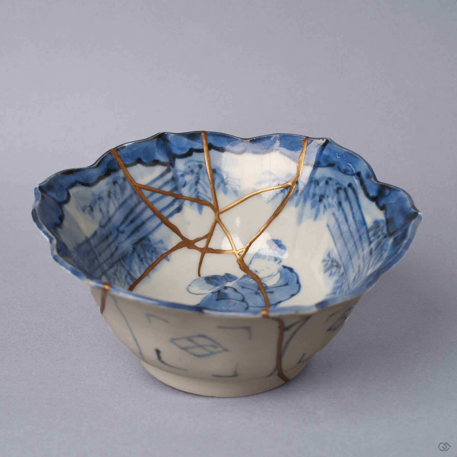 Front view of a Ko-Imari kintsugi bowl, foliate rim, cobalt landscape interior with 24K gold seams within and pure silver seams along the outer wall, restored with natural urushi.