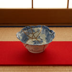 Ko-Imari blue-and-white kintsugi bowl set on a tatami mat with a red runner, its cobalt sage-and-bamboo interior and 24K gold seams shown within a quiet Japanese interior.